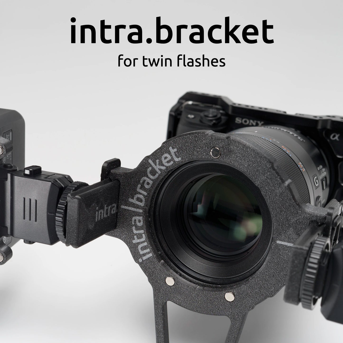 Camera with intra bracket for twin flashes on a light gray background